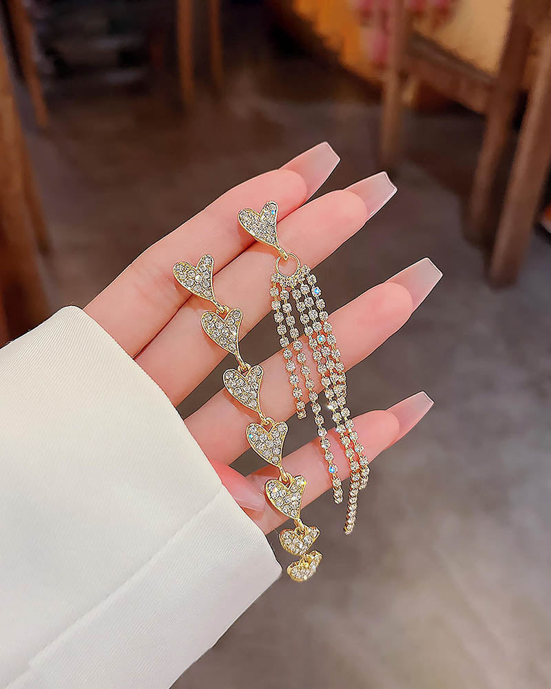Elegant heart-shaped earrings with beads on a hand against a blurred indoor background